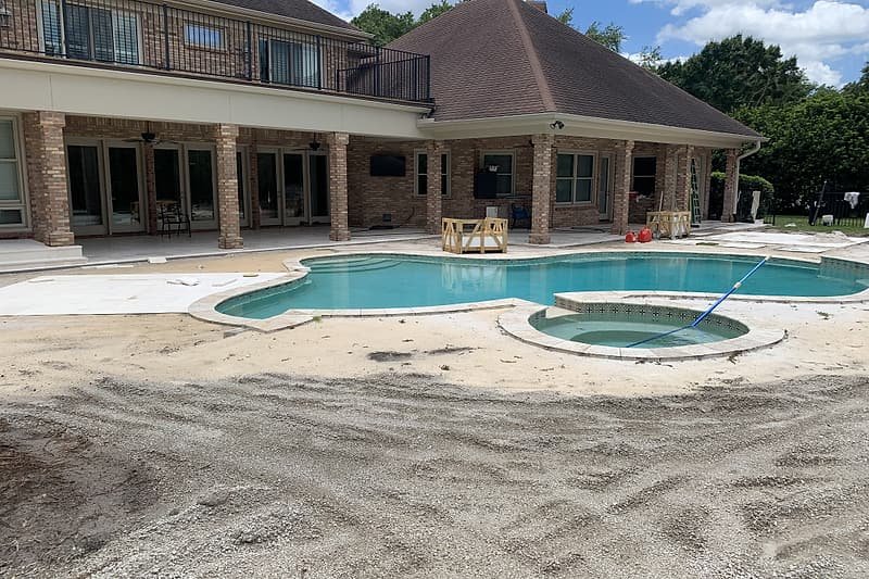 Pool backyard before the project, with bare sand where the old deck was removed