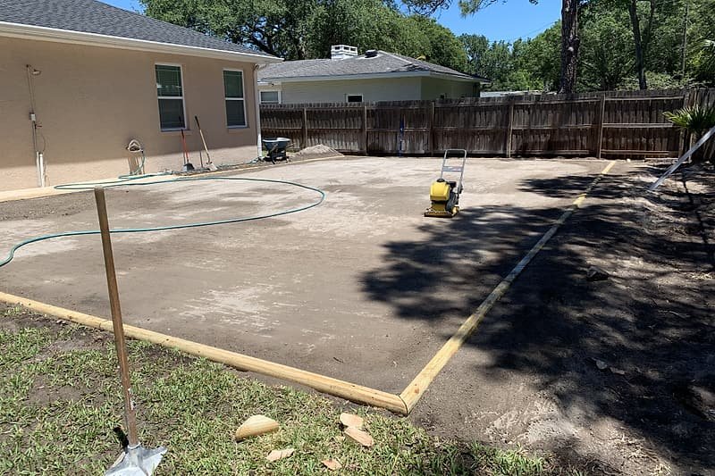 Compacted base with wood forms and a plate compactor, ready for the next layer
