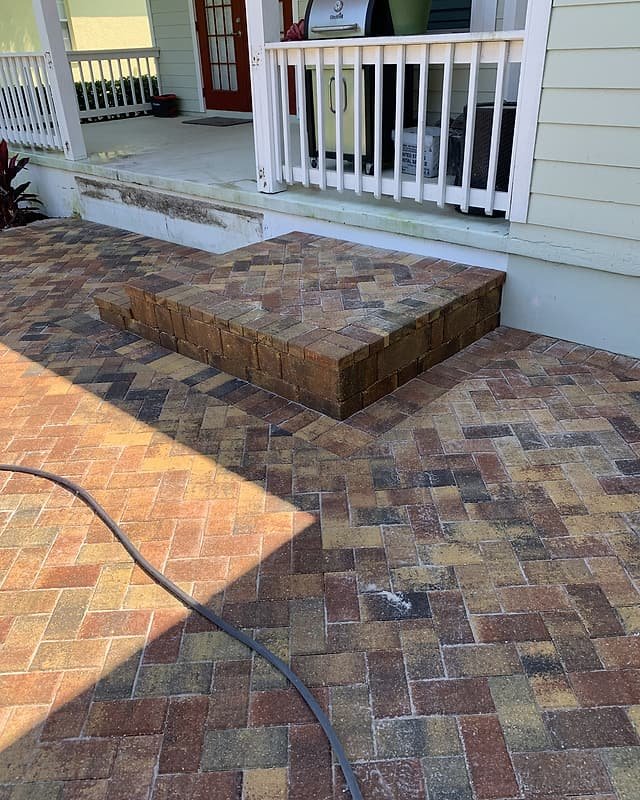 Brick paver landing and step at the base of a front porch