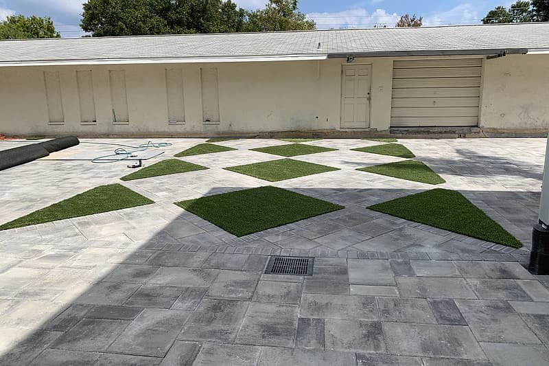 Paver courtyard with diamond-shaped inlays of artificial turf in a checkerboard pattern