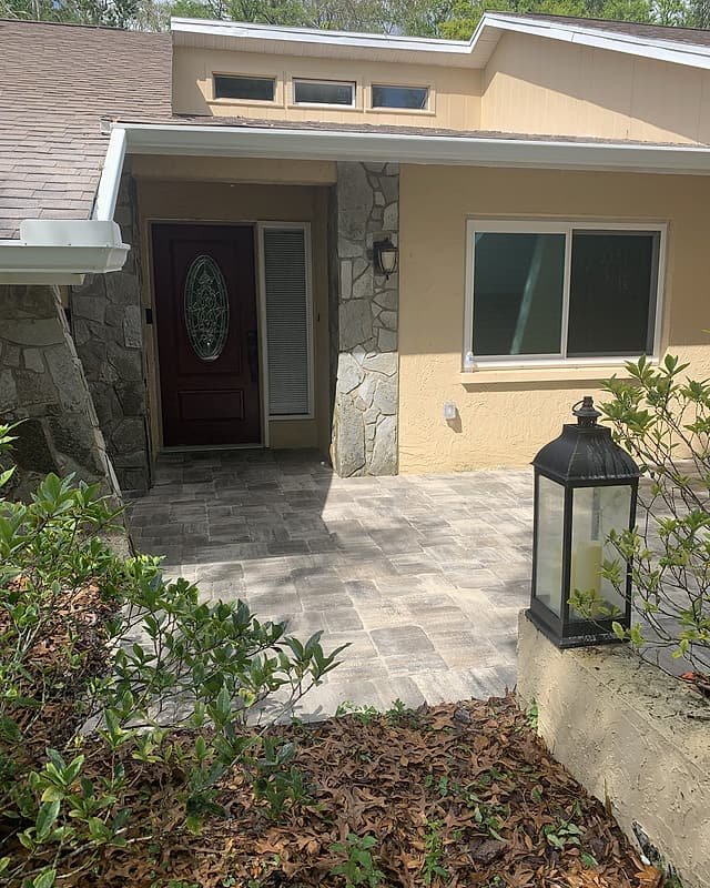 Front entry walkway in pavers leading to the door of a stone-trimmed home