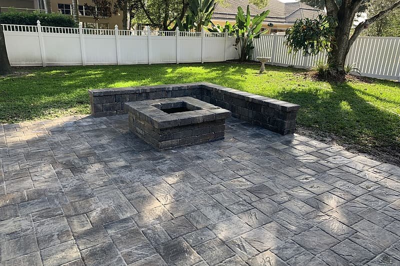 Paver patio with a square fire pit and a curved block seating wall