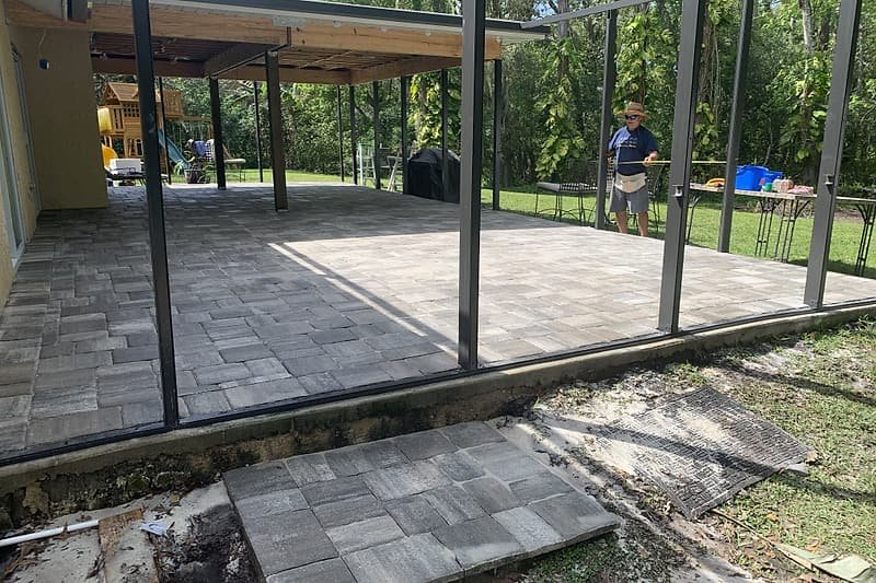 Screened patio with new pavers and spare pavers stacked for the next section