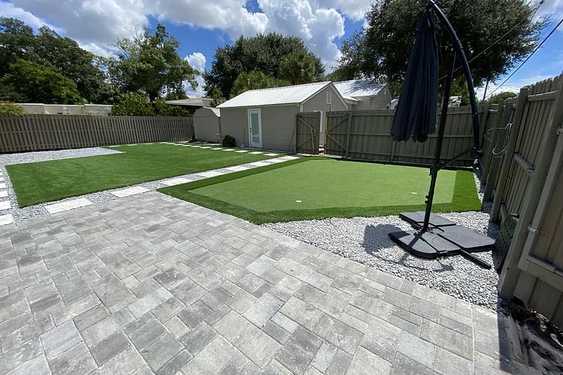 Paver patio, artificial turf lawn and putting green in a fenced backyard