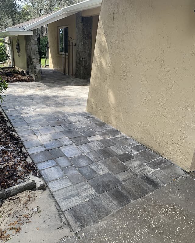 Paver walkway running along the side of a house