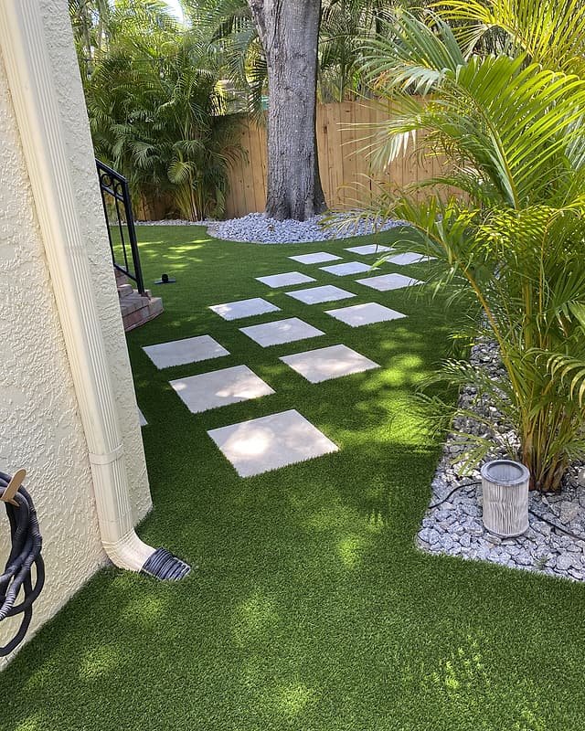 Shaded side yard with artificial turf, a stepping-stone path and tropical planting
