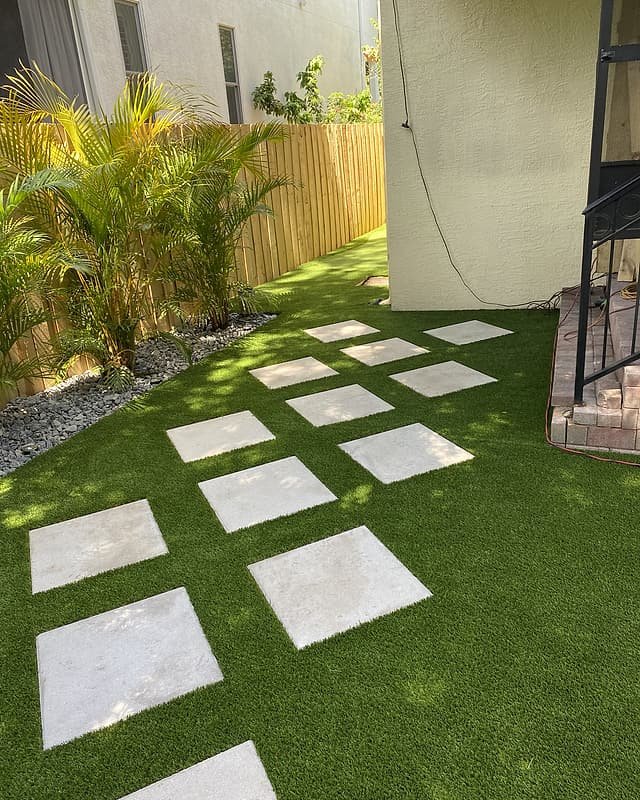 Artificial turf side yard with square stepping stones beside the house