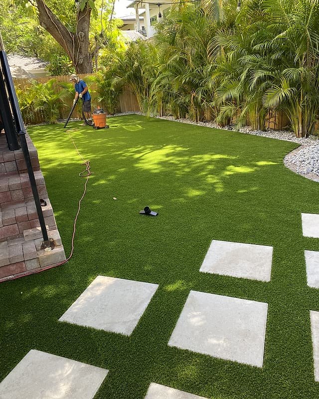 Artificial turf with large square stepping stones in a fenced side yard