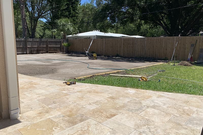 Travertine patio edge meeting the lawn before artificial turf installation