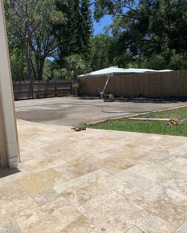Travertine pavers in a French pattern beside the house