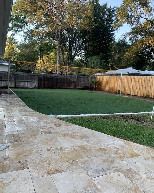 Travertine walkway curving along a new artificial turf lawn